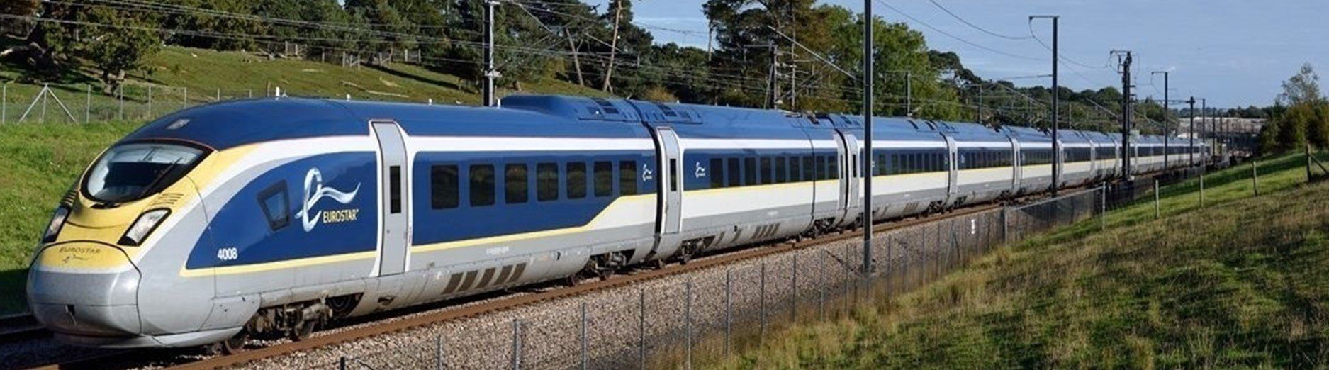 a blue, grey and yellow train on train tracks viewed from a front/side angle